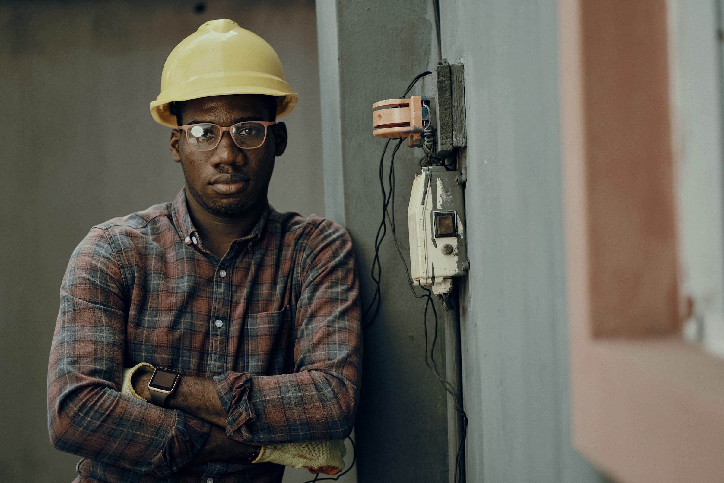 Electrician in hard hat beside a service panel — concept photograph