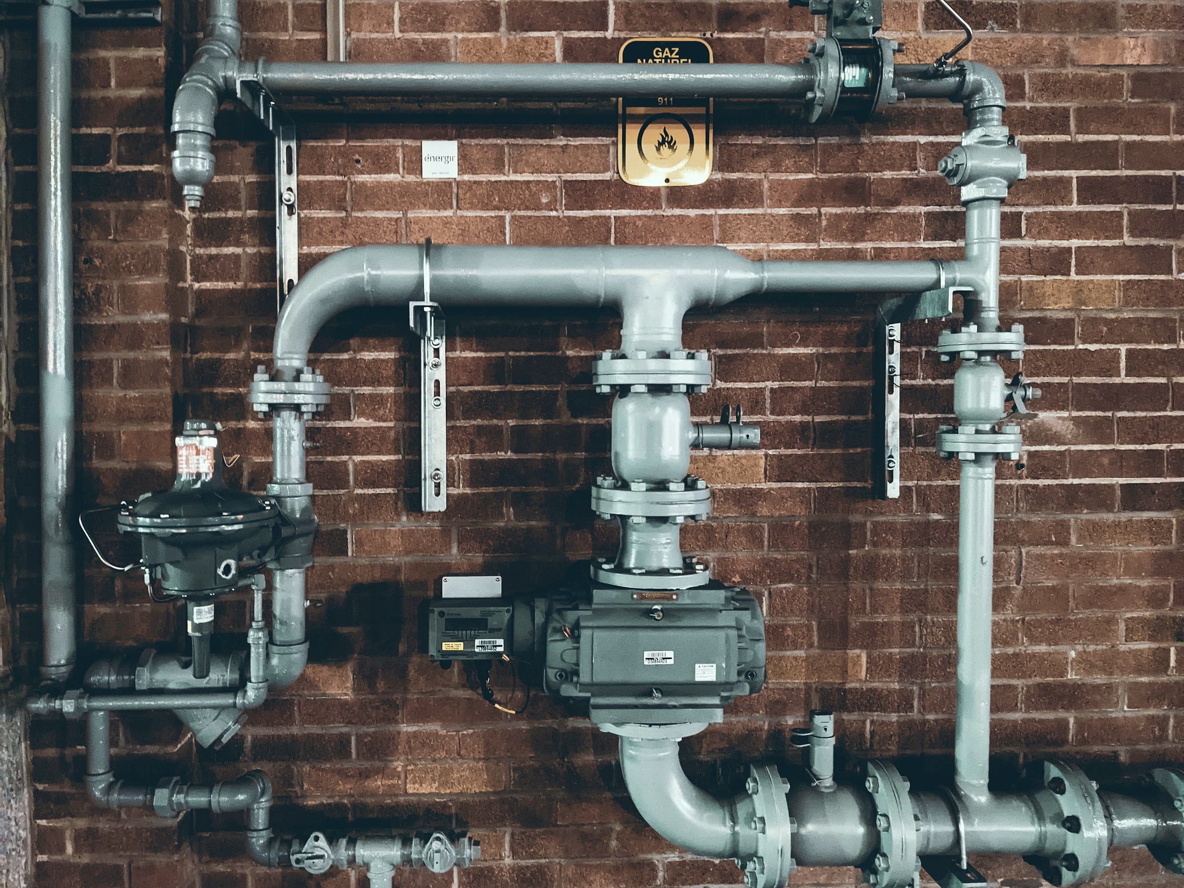 Mounted pipe system and valves on brick — concept photograph