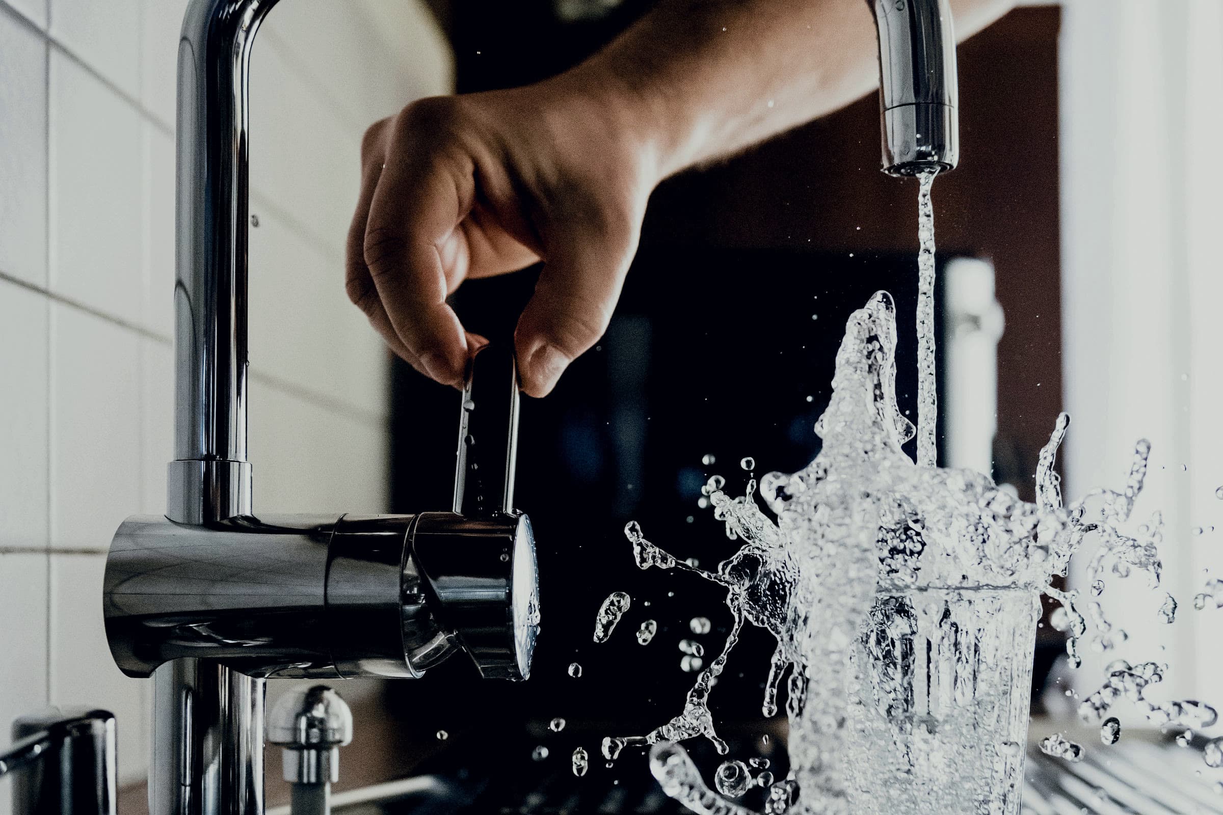 Hand at a faucet with water in motion — concept photograph